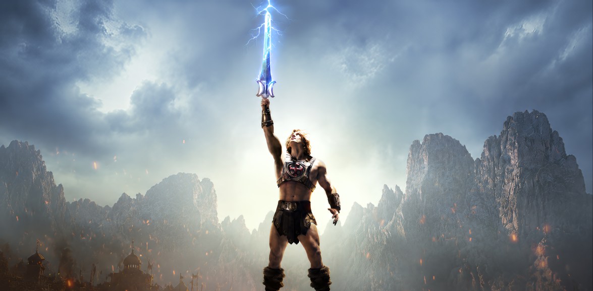 He-Man stands on a rocky ridge with the electrically charged Sword of Power raised high beneath the blue-grey sky of Eternia