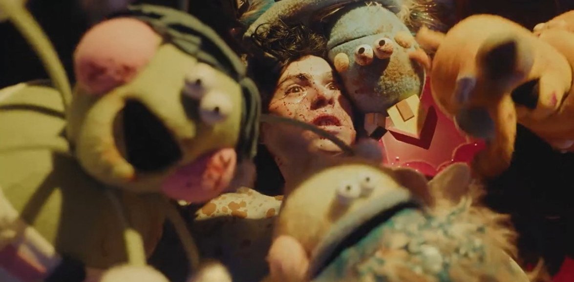 Colourful homicidal puppets surround a victim in the horror anthology V/H/S/Mixtape (2026).